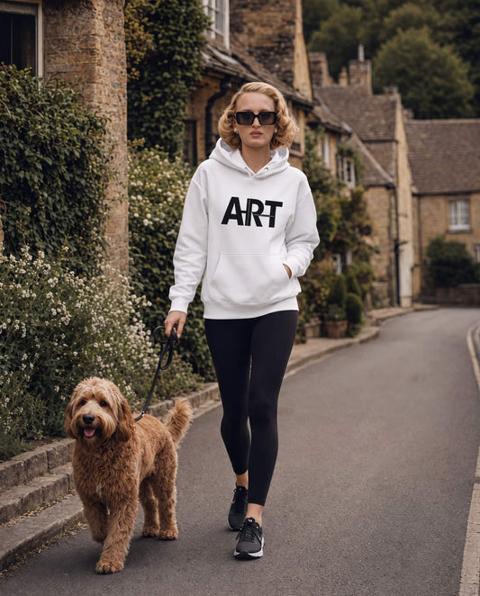 Woman walking a dog on a street wearing a hoodie with 'ART' printed on it.